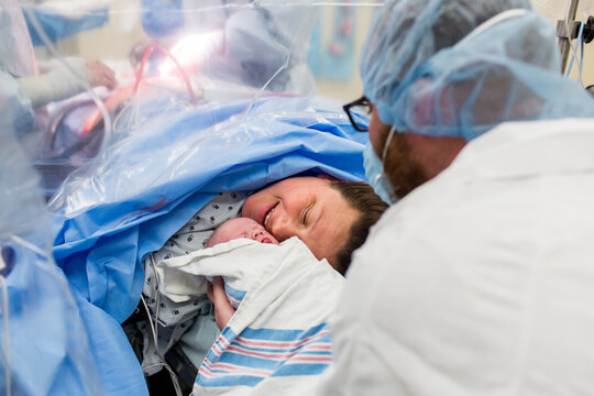Mom Smiling While Meeting Baby After C-Section on Operating Table