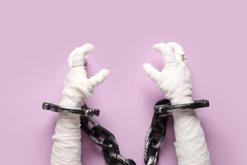 Mummy hands in chain on purple background. Halloween celebration