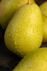 a green ripe pear covered with drops of water on the table