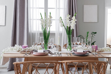 Beautiful table setting with white Gladiolus flowers and burning candles in room