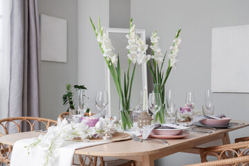 Beautiful table setting with white Gladiolus flowers and burning candles in room