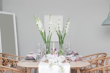 Beautiful table setting with white Gladiolus flowers and burning candles in room