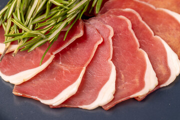 sliced ham with bacon on a board