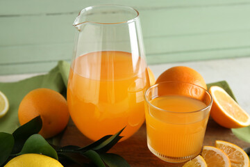 Glass and jug of fresh orange juice and fruits on white table