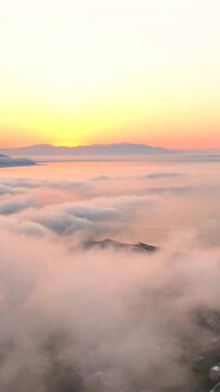 Volando sopra le nuvole all'alba con il sole giallo che spunta.
Ripresa aerea tra le nuvole, sole, mare e montagna. San Felice Circeo, Lazio, Italia.  Video verticale.