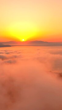 Volando sopra le nuvole all'alba con il sole giallo che spunta.
Ripresa aerea tra le nuvole, sole, mare e montagna. San Felice Circeo, Lazio, Italia.  Video verticale.