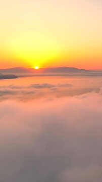 Volando sopra le nuvole all'alba con il sole giallo che spunta.
Ripresa aerea tra le nuvole, sole, mare e montagna. San Felice Circeo, Lazio, Italia.  Video verticale.