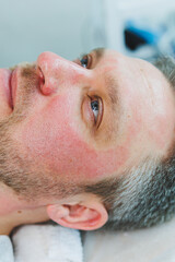 A cosmetologist cleans the skin of a man's face. A man does facial procedures in a cosmetic clinic. Male cosmetology.