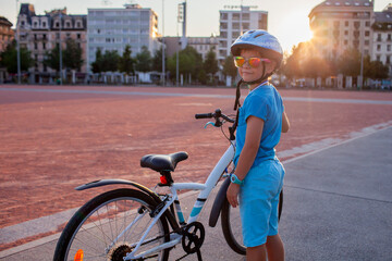 Fototapeta premium A happy youngster rides a bicycle in a vibrant city setting. The scene highlights the energy and well-being gained from cycling, promoting an active lifestyle with an emphasis on safety.