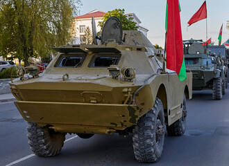 Fototapeta premium Military vehicles driving down a city street during a parade with flags displayed
