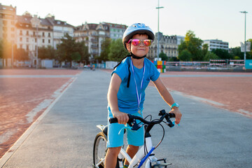 A cheerful child rides a bicycle through the city, wearing a helmet for safety