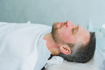A cosmetologist cleans the skin of a man's face. A man does facial procedures in a cosmetic clinic. Male cosmetology.