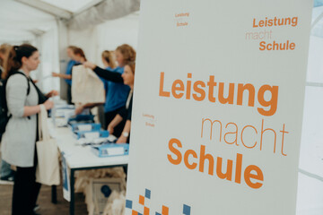 Kongressanmeldung mit Kongressbanner im Vordergrund - Leistung macht Schule