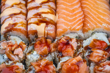 Colorful sushi rolls displayed on a platter, showcasing salmon, shrimp, and savory sauces