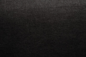 A textured close-up of dark fabric illuminated by soft lighting in an indoor setting