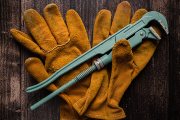 Adjustable gas wrench in glove on wooden table