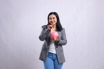 portrait of beautiful young woman office smile carrying money coins and piggy bank for saving wearing suit isolated on white background. concept of advertising, education, safe money, lifestyle