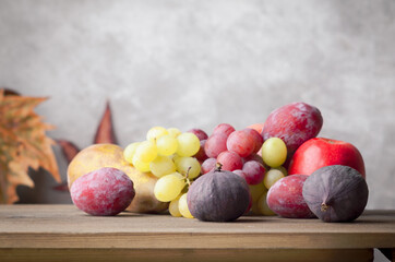 Autumn fruit on wooden table on grey light background. Grape, pears figs and plums. 