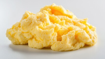 Fluffy scrambled eggs with a smooth texture, sitting on a white surface, offering a fresh and simple breakfast presentation.