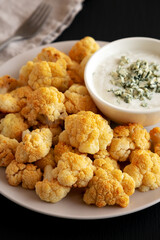 Homemade Buffalo Cauliflower with Blue Cheese Sauce on a Plate on a Black Background, side view.