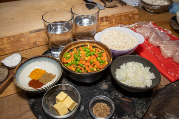 A selection of ingredients use to make an Indian Curry Chicken Biriyani showing the food prepped to make the traditional Indian dish on a wooden kitchen table