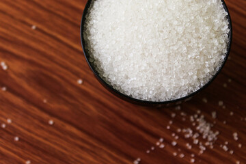 White sugar in bowl on wood background. selective focus with blur
