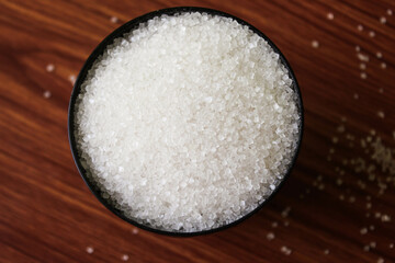 White sugar in bowl on wood background. selective focus with blur
