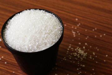 White sugar in bowl on wood background. selective focus with blur
