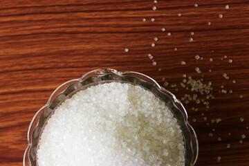 White sugar in bowl on wood background. selective focus with blur

