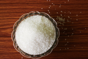 White sugar in bowl on wood background. selective focus with blur
