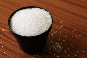 White sugar in bowl on wood background. selective focus with blur
