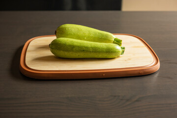Two Fresh Zucchini on a Cutting Board Close-Up on Dark Background
