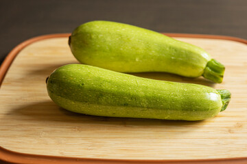 Two Fresh Zucchini on a Cutting Board Close-Up on Dark Background