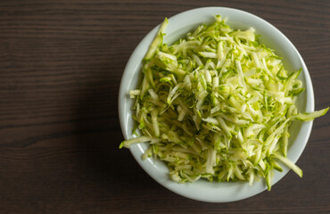 Shredded Zucchini in a White Bowl Close-Up on Dark Background