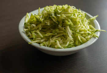  Shredded Zucchini in a White Bowl Close-Up on Dark Background