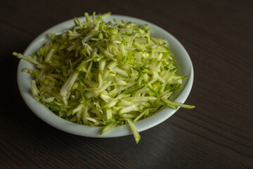  Shredded Zucchini in a White Bowl Close-Up on Dark Background