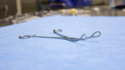 Fototapeta premium Stainless surgical sponge holding forceps placed on a blue background. Medical equipment used in surgery. Surgical instruments. Medical science and surgery concept.