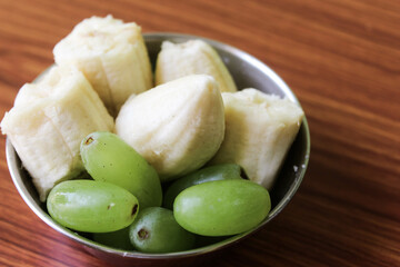 Delicious fresh fruit salad in bowl on brown wooden background