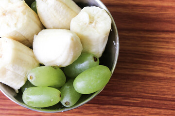 Delicious fresh fruit salad in bowl on brown wooden background