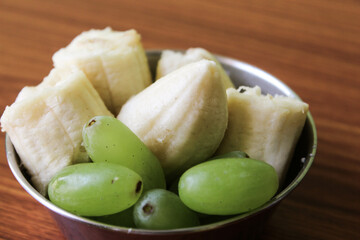 Delicious fresh fruit salad in bowl on brown wooden background