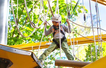 brave little boy in helmet climbing at adventure park in autumn season. Work out concept