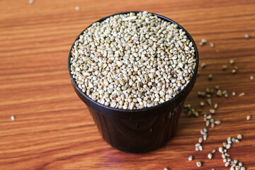 Organic Pearl Millet (Pennisetum glaucum) or Bajra, in a bowl. Isolated on a brown wooden background.selective focus with blur

