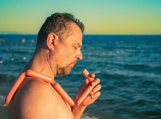 Sad mature man topless posing with barbecue sausages on against the sea. Concept travelling, party,...