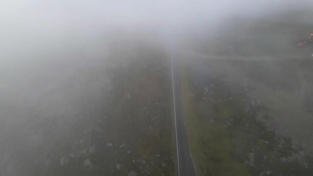Drone shot flying through thick fog following the Applecross pass road over the Bealach na B&agrave; pass in the Scottish highlands.