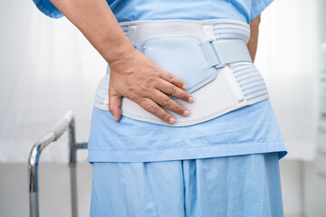 Asian lady patient wearing back pain support belt for orthopedic lumbar with walker.