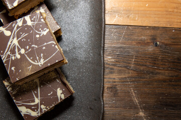 A delicious pile of Millionaires Flapjacks chocolate and toffee sweet treats on a wooden kitchen worktop or table
