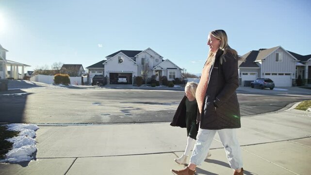 Pregnant mother walks with child in serene suburban neighborhood during winter