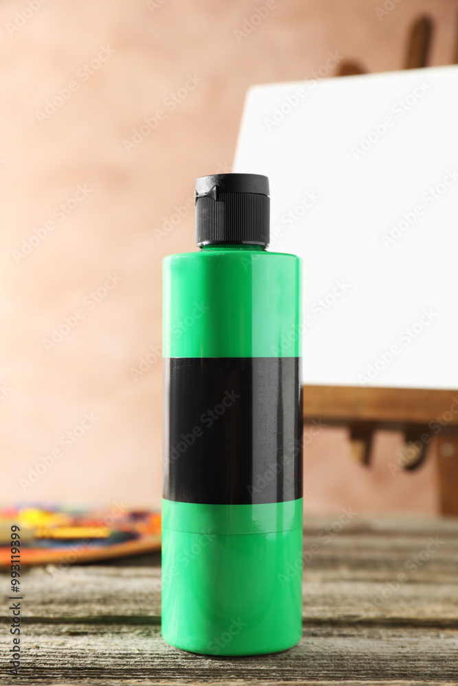 Sticker Green acrylic paint in bottle on wooden table