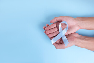 Prostate cancer awareness. Man with light blue ribbon as symbol of support on color background, top...