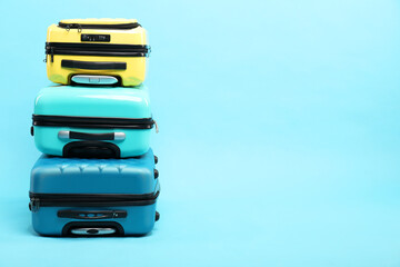 Stack of different suitcases on light blue background, space for text